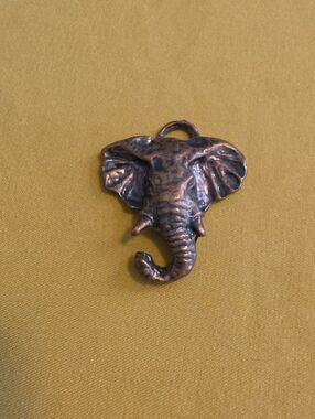 Vintage-style elephant head pendant or charm with an antiqued copper finish.